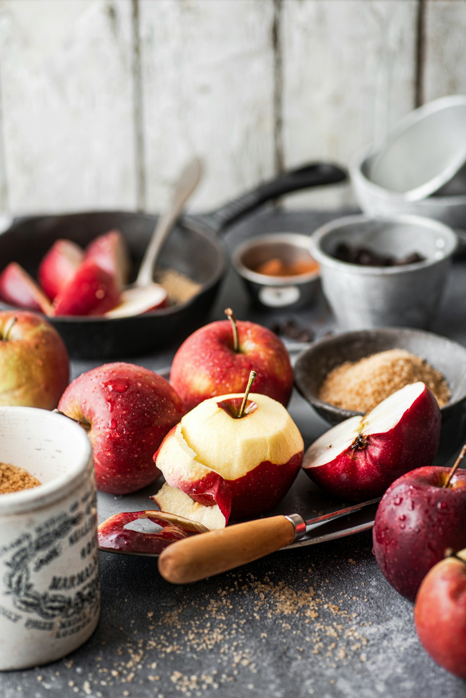 Various apples being peeled with spoons and knives.