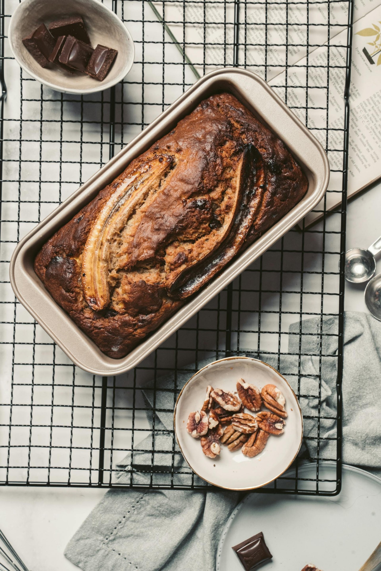 A loaf of banana bread in the pan on a cooling rack.