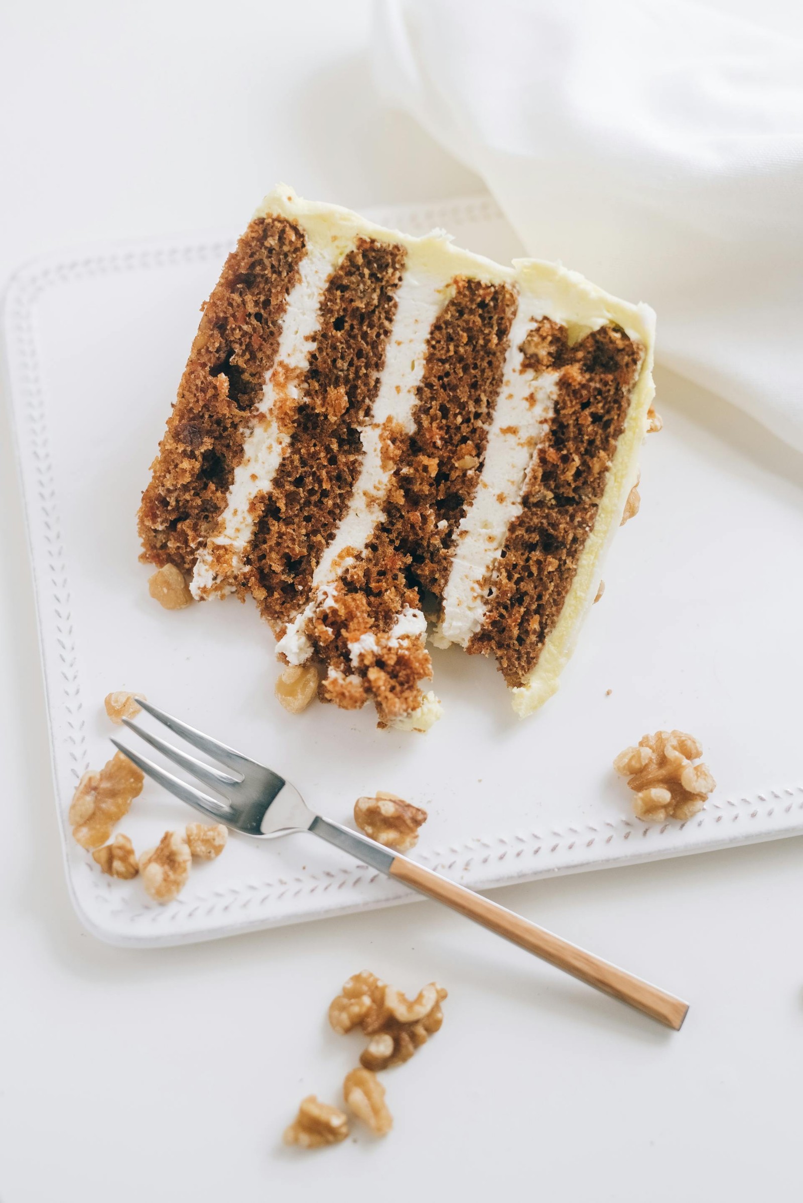 A slice of carrot cake on a white cake.