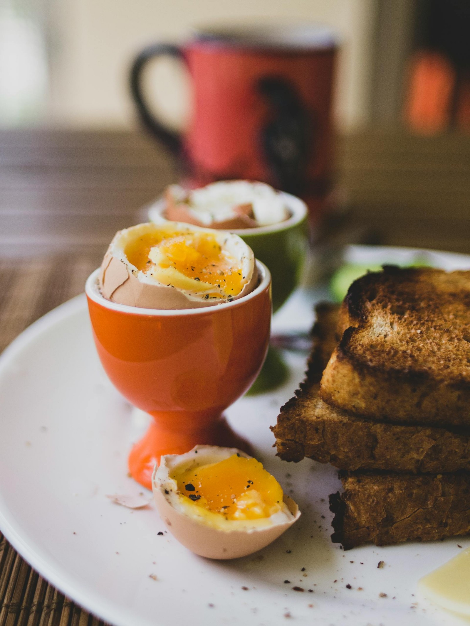 A boiled egg in an egg cup with a stack of toast beside it.