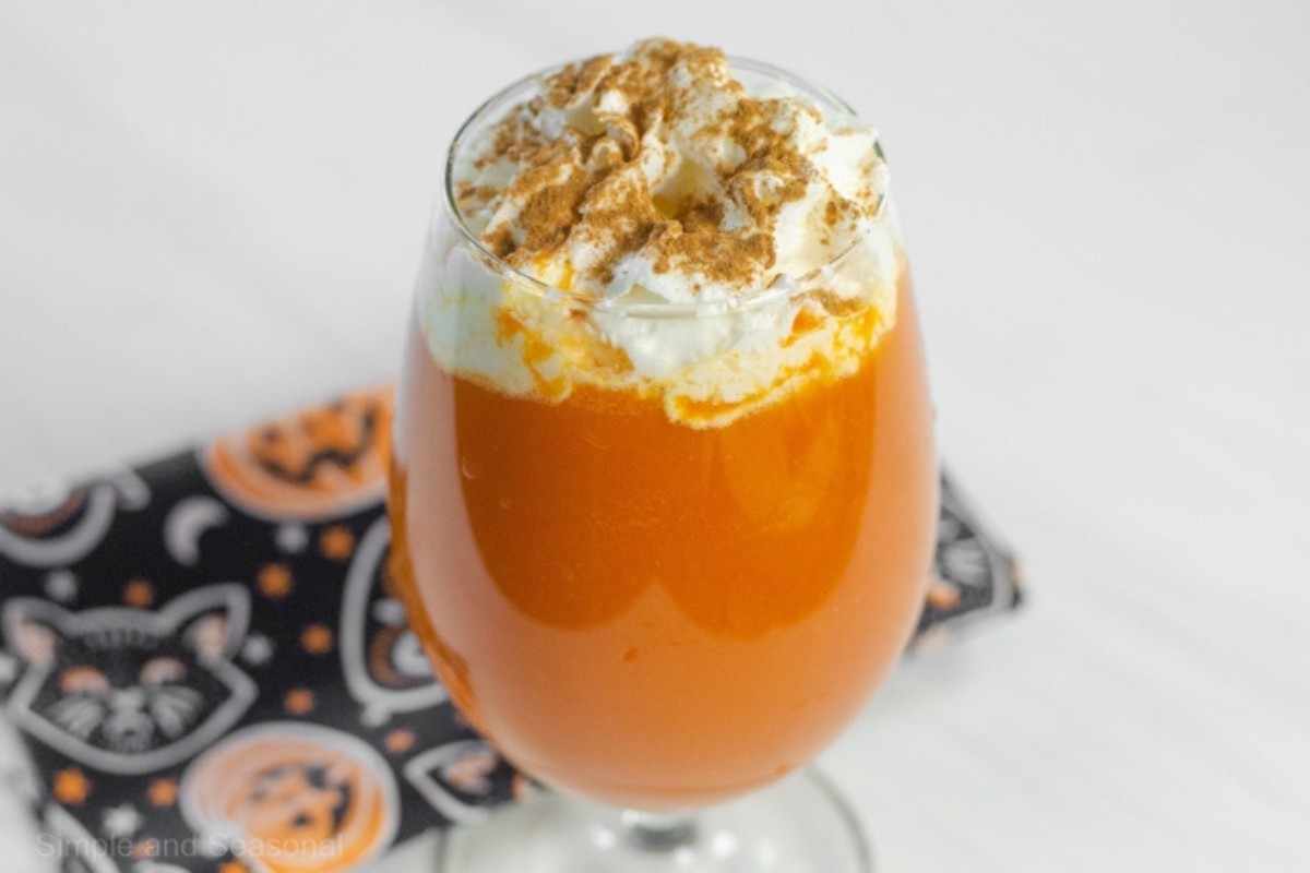 A glass filled with Pumpkin pie Punch with whipped topping and granola.