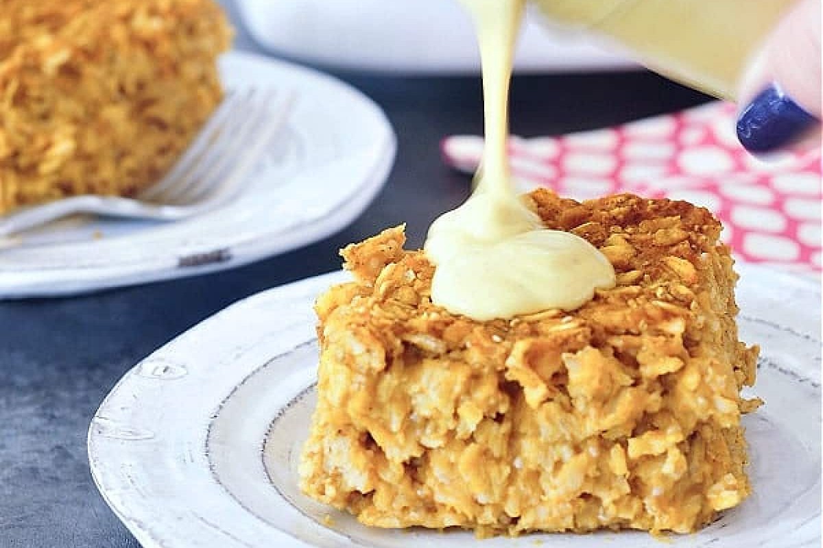A serving size of baked pumpkin oatmeal with a frosting being poured over it. 